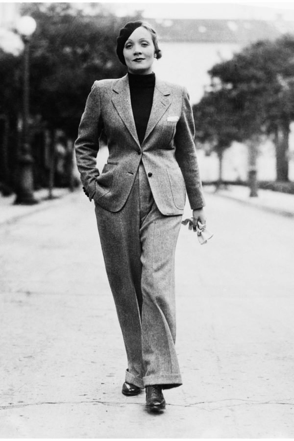 25 Jan 1933 --- Wearing a beret and carrying gloves, Marlene Dietrich, prominent Paramount screen star, jauntily strolls along Hollywood Street attired in a grey man's suit, with turtle-neck sweater.  Stylists declare this mode set by Marlene will sweep the country--which probably means that men will have to find themselves some cute tailored skirts. --- Image by © Bettmann/CORBIS